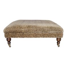 a leopard print footstool with wooden legs and an upholstered cushion on top