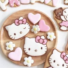 hello kitty cookies are arranged on a wooden plate next to some cut out hearts and flowers