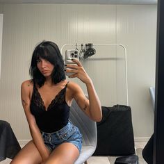 a woman taking a selfie while sitting on a chair in front of a mirror