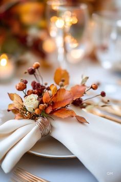 a white plate topped with a napkin covered in flowers and leaves next to a fork