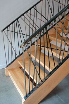 a wooden stair case with metal handrails on the bottom and top treads