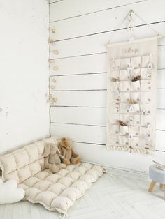 a teddy bear sitting on a couch in a room with white walls and wood flooring