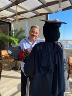 a man in a graduation cap and gown is being congratulated by another man