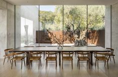 a dining room with large windows and wooden chairs