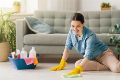 a woman cleaning the floor in her living room with yellow rubber gloves and sponges