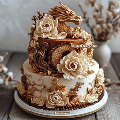 a three tiered cake decorated with flowers and a dragon on the top is sitting on a wooden table