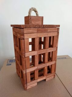 a building made out of wooden blocks sitting on top of a cardboard box with a rope hanging from it