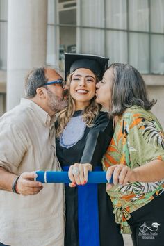 a woman kissing a man on the cheek while he is wearing a graduation cap and gown