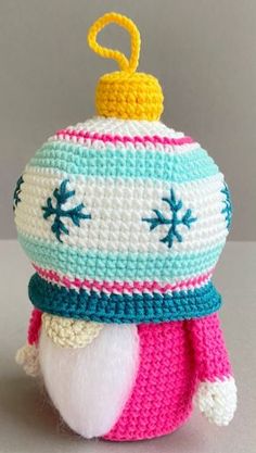 a crocheted ornament with a yellow top and blue, white, pink, and green trim