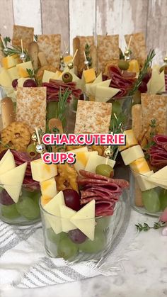 an arrangement of cheeses, crackers and olives in glass bowls