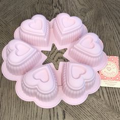 four heart shaped cake pans sitting on top of a wooden table next to a card