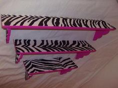 two pink and black zebra print shelfs on a bed