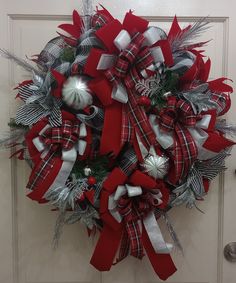 a red and white christmas wreath hanging on the front door