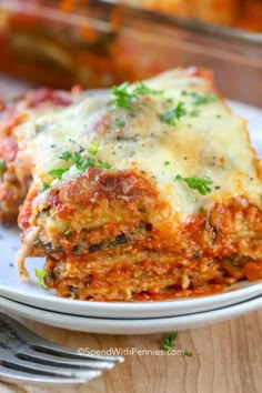 a white plate topped with lasagna covered in sauce and parmesan cheese