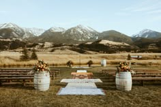 an outdoor ceremony setup with wine barrels and flowers on the table in front of mountains