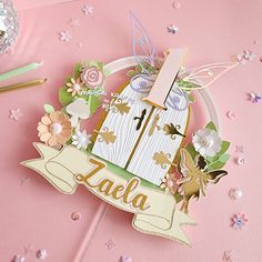 a pink table topped with lots of paper flowers and a wooden sign that says lala