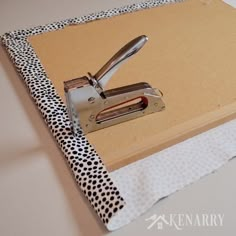 a pair of staplers on top of a binder with polka dot print fabric