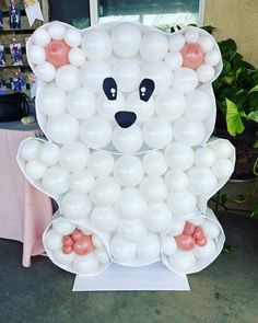 a large white bear made out of balloons on a table in front of a window