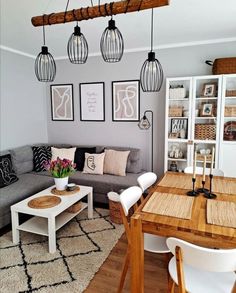 a living room filled with furniture next to a wooden table and white chairs on top of a hard wood floor