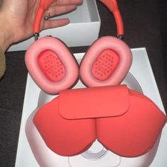 a pair of red headphones sitting on top of a white box next to a person's hand