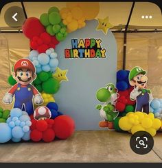 an image of a birthday party with balloons and mario bros characters on the stage set up