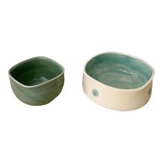 two bowls are sitting next to each other on a white surface, one is green and the other is light blue