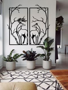 a living room filled with furniture and plants in front of two paintings on the wall