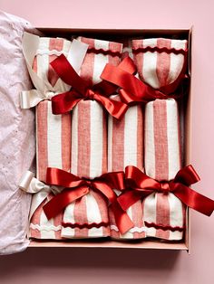 four red and white striped napkins in a box with ribbons on them, tied together