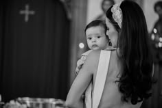 a woman holding a baby in her arms while standing next to other people at a table