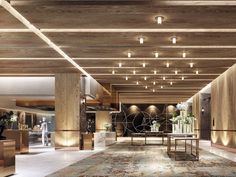 an empty lobby with wooden walls and flooring on the ceiling is lit by recessed lights