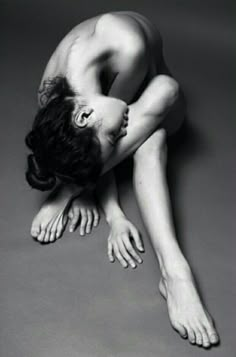 a naked woman laying on the ground with her head down and hands behind her back