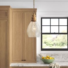 a kitchen with marble counter tops and wooden cabinets, along with a bowl of fruit