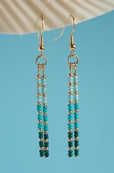 two blue beads hanging from the side of a pair of earrings