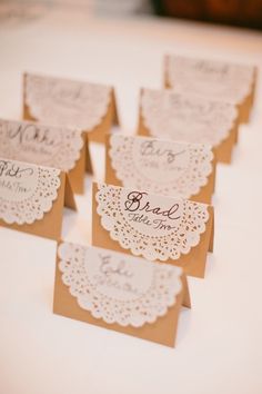 some cards with doily on them are being used to make place cards for wedding guests