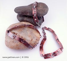 two pieces of metal sitting on top of a rock next to a pair of bracelets