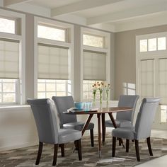 a dinning room table with four chairs and a bowl of flowers on the table