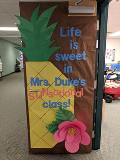 a bulletin board with a pineapple on it in the middle of an office hallway