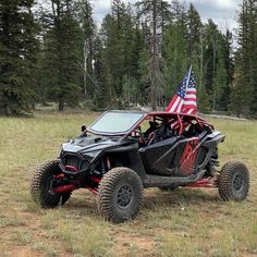 a black and red four - wheeled vehicle with an american flag on the windshield parked in a field