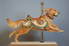 a wooden carousel horse with an animal on it's back legs and tail, standing upright