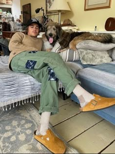 a man sitting on a bed with his dog in front of him and two stuffed animals behind him