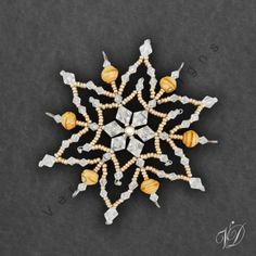 a beaded snowflake is shown on a black surface with white and yellow beads