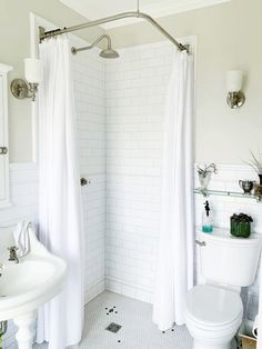 a white bathroom with a shower, toilet and sink in it's corner area