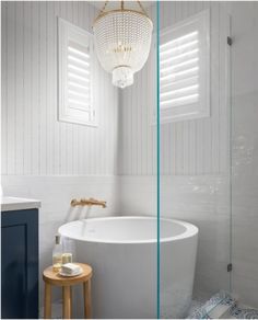 a white bath tub sitting next to a walk in shower under a chandelier