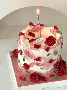 a birthday cake with roses on it and a single candle in the middle that is lit