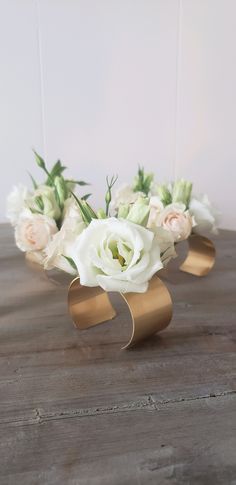 some white and pink flowers are on a wooden table with gold tape around it's edges