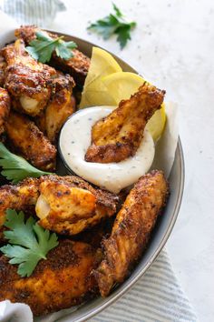 a bowl filled with chicken wings and garnished with parsley