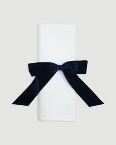 a white towel with a blue bow on it's end and black ribbon around the edge