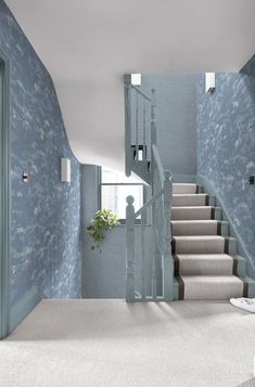 a room with blue walls and white carpeted stairs leading up to the second floor