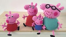 crocheted peppa pig family sitting on top of a wooden table next to each other