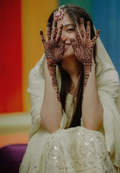 a woman with her hands on her face covered in hendix and holding her eyes closed